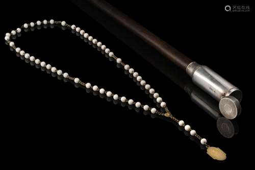 A wooden walking stick with silver handle enclosing a rosary...