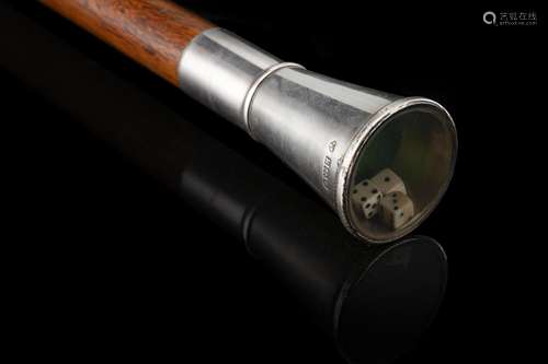 A walking stick with a silver handle enclosing three dice in...