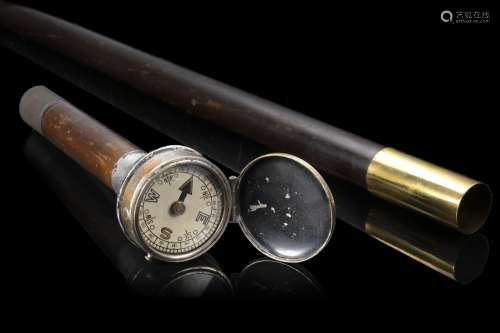An ebony walking stick with a compass in the silver and silv...