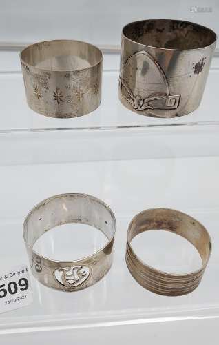 Four various silver marked napkin rings together with an orn...