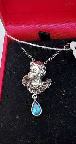 A silver pendant necklace of a figure with pear shaped blue ...