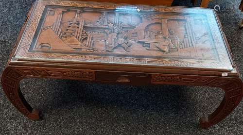 An oriental hand carved coffee table with glass top section....