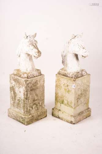A pair of reconstituted stone horse's heads on plinth bases ...