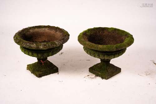 A pair of weathered reconstituted stone campana garden urns,...