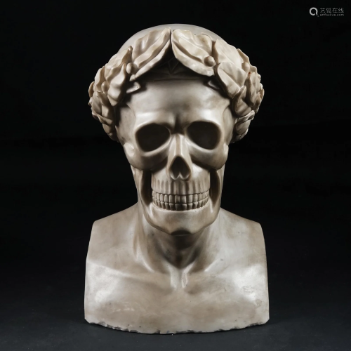 A white marble bust of a skull with a laurel wreath