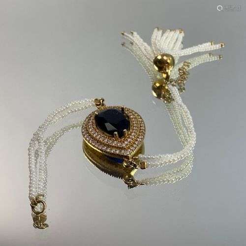 Bracelet en métal doré orné d'une pierre bleue pyriforme dan...