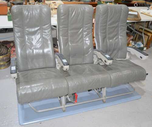 A set of three vintage aeroplane seats upholstered in grey l...