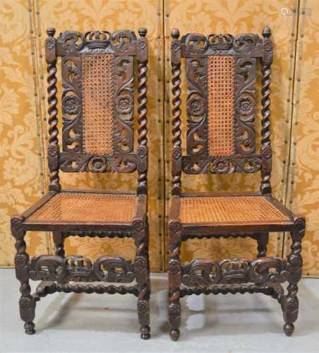 A pair of Carolean walnut hall chairs carved with scroll wor...
