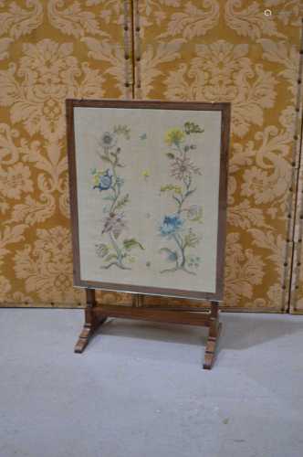 A Victorian needlework tapestry fire screen in an oak frame