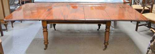 A Victorian mahogany dining table on turned legs, with brass...