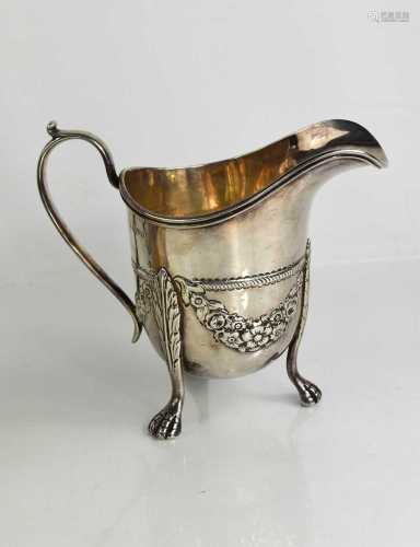 A silver footed jug, embossed with floral swags and raised o...