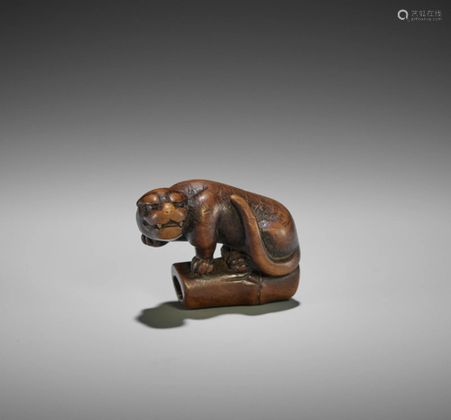 A KYOTO SCHOOL WOOD NETSUKE OF A TIGER ON BAMBOO