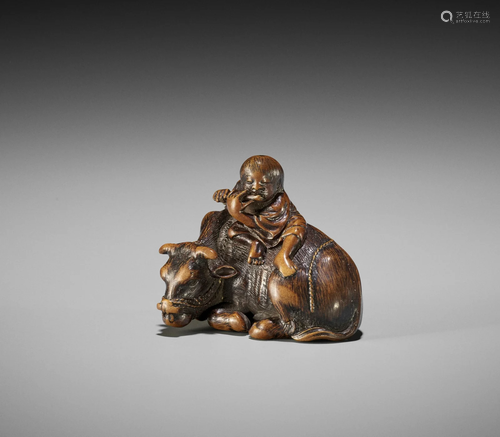 AN EXQUISITE WOOD NETSUKE OF A HERDBOY ON OX