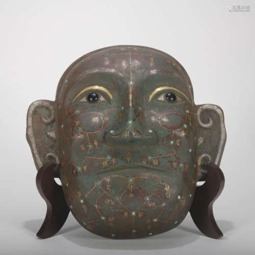 A bronze mask ware with gold and silver