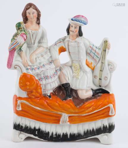 A Staffordshire pottery figural group of a couple on a sette...