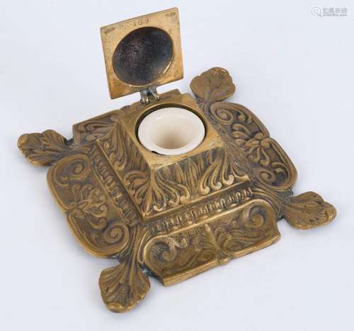 An antique English cast brass ink well with ceramic ink pot,...