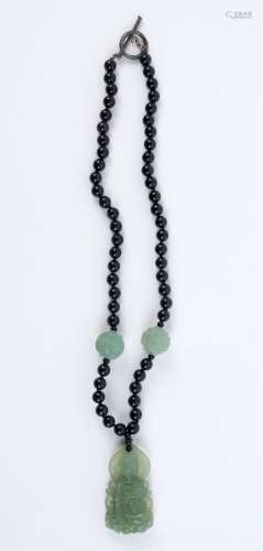 A Chinese green jade Buddha necklace with black glass beads,...