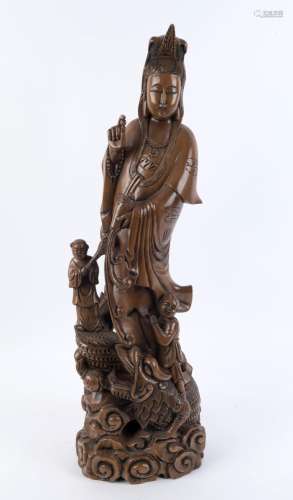 A Chinese carved wooden statue of Guanyin standing on a wate...