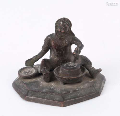 An Indian bronze statue of a seated figure with grinding sto...