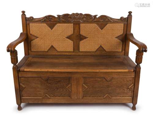 A Tudor revival hall seat, carved oak with caned back and li...
