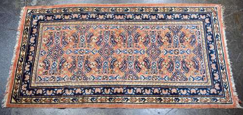A small Persian hand-knotted wool rug, pink ground with blue...