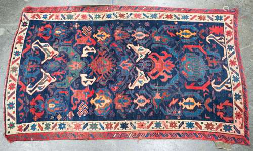 A Persian hand-knotted rug with dark blue ground and red bor...