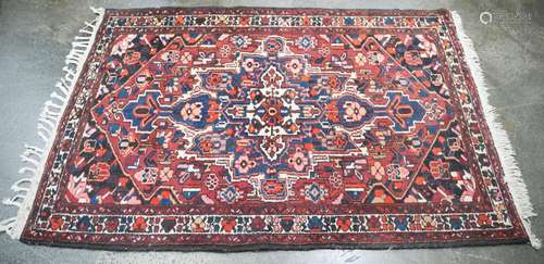 A Persian hand-knotted wool rug with red and blue ground, 23...