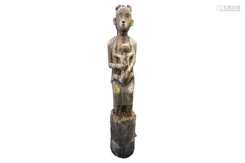 A large Javanese carved wood statue of a standing mother clu...