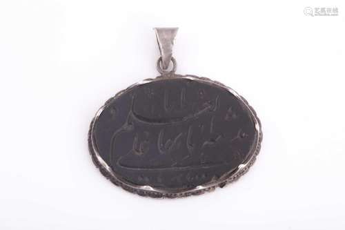 A Safavid carved dark green jade pendant in silver metal mou...