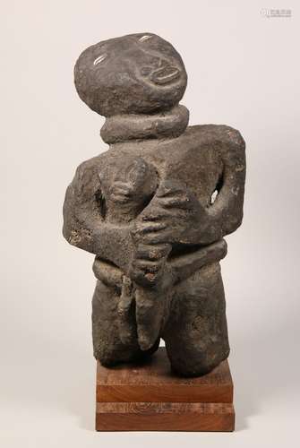 Cameroon, Tikar, stone statue of a female figure holding her...