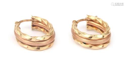 A pair of 14 karat gold two tone hoop earrings. In rose and ...