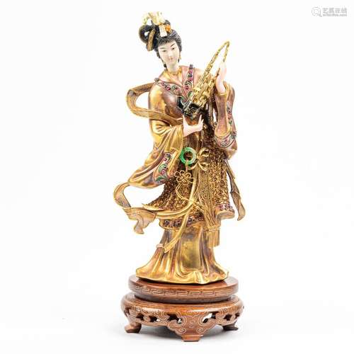 A statue of a musical figurine with a Sheng music instrument...