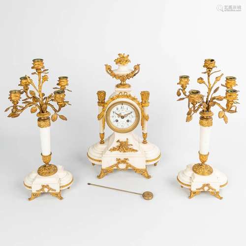 A three-piece mantle garniture with a clock and two candelab...