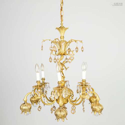 A chandelier made of brass and glass, decorated with birds a...