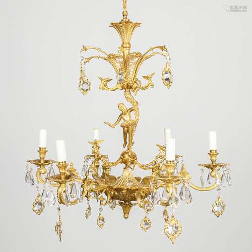 A chandelier made of brass and glass, decorated with birds a...