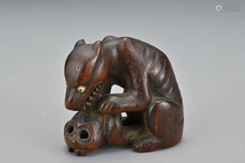 A Japanese carved wood netsuke in the form of a wolf