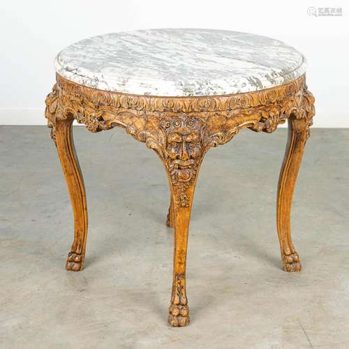 An antique round side table finished with wood sculptures an...