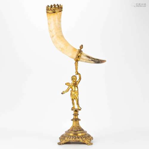 A horn on a bronze stand and decorated with an angel.