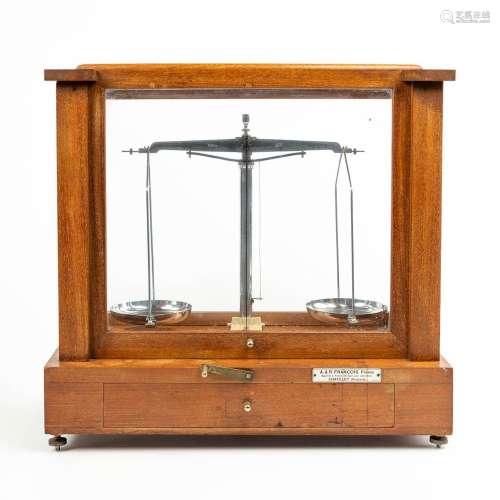 A pharmacy precision scale in a box made of wood and glass a...