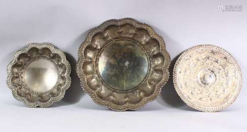 THREE INDIAN WHITE METAL EMBOSSED DISHES - each of varied de...