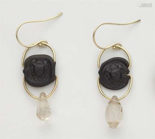 A pair of 14k gold earrings with ancient amulets