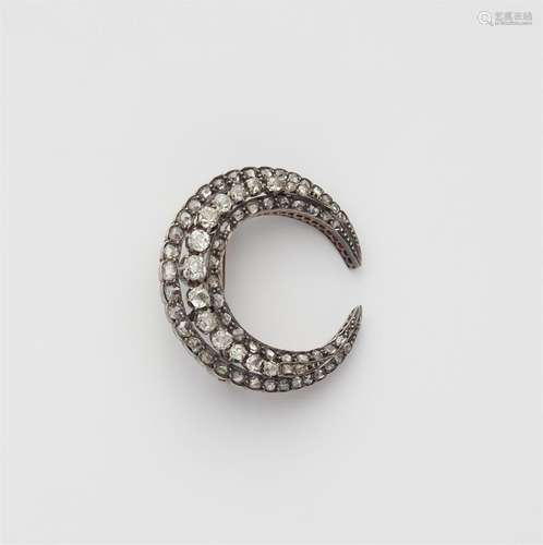 A silver and 14k gold diamond crescent moon brooch