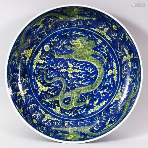 A CHINESE BLUE GROUND PORCELAIN DRAGON DISH, the centre pain...