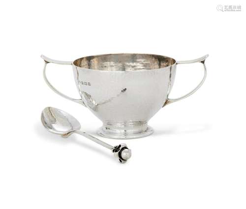 AN ARTS AND CRAFTS HAMMERED SILVER CHRISTENING BOWL AND SPOO...