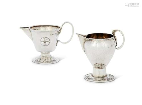 TWO ARTS AND CRAFTS HAMMERED SILVER CREAM JUGS BY A.E. JONES...