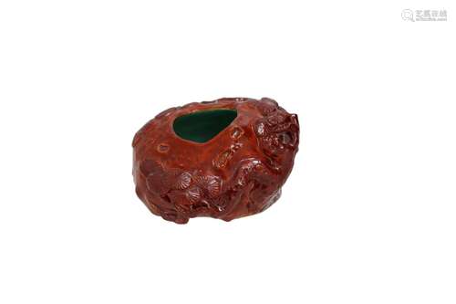 A red glazed porcelain ink pot with relief decor ofa blossom...