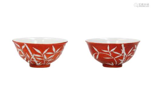 A pair of coral red and white porcelain cups, decorated with...