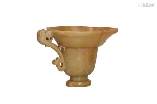 A carved soapstone libation cup with handle in the shape of ...