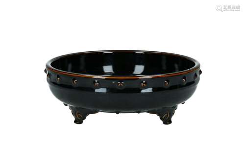 A brown glazed porcelain tripod bowl with relief decor of do...