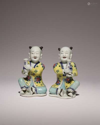 A PAIR OF CHINESE FAMILLE ROSE MODELS OF SEATED BOYS 18TH CE...